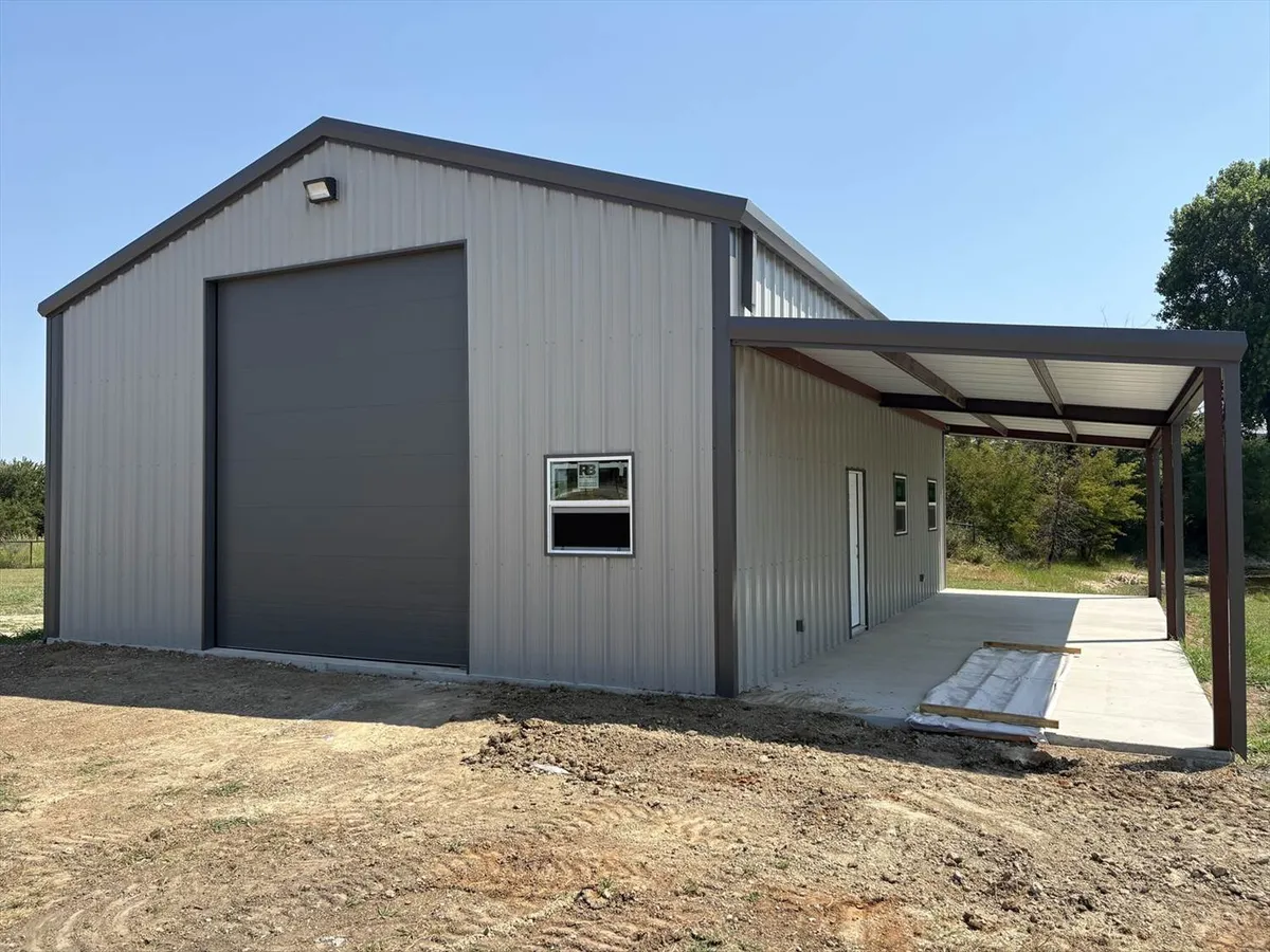 Exterior view of a newly constructed residential metal shop building with a covered patio area and concrete foundation