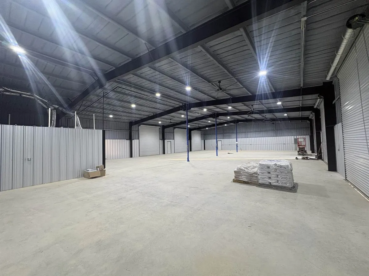 Interior view of a large commercial warehouse showing high bay LED lighting installed across the open space