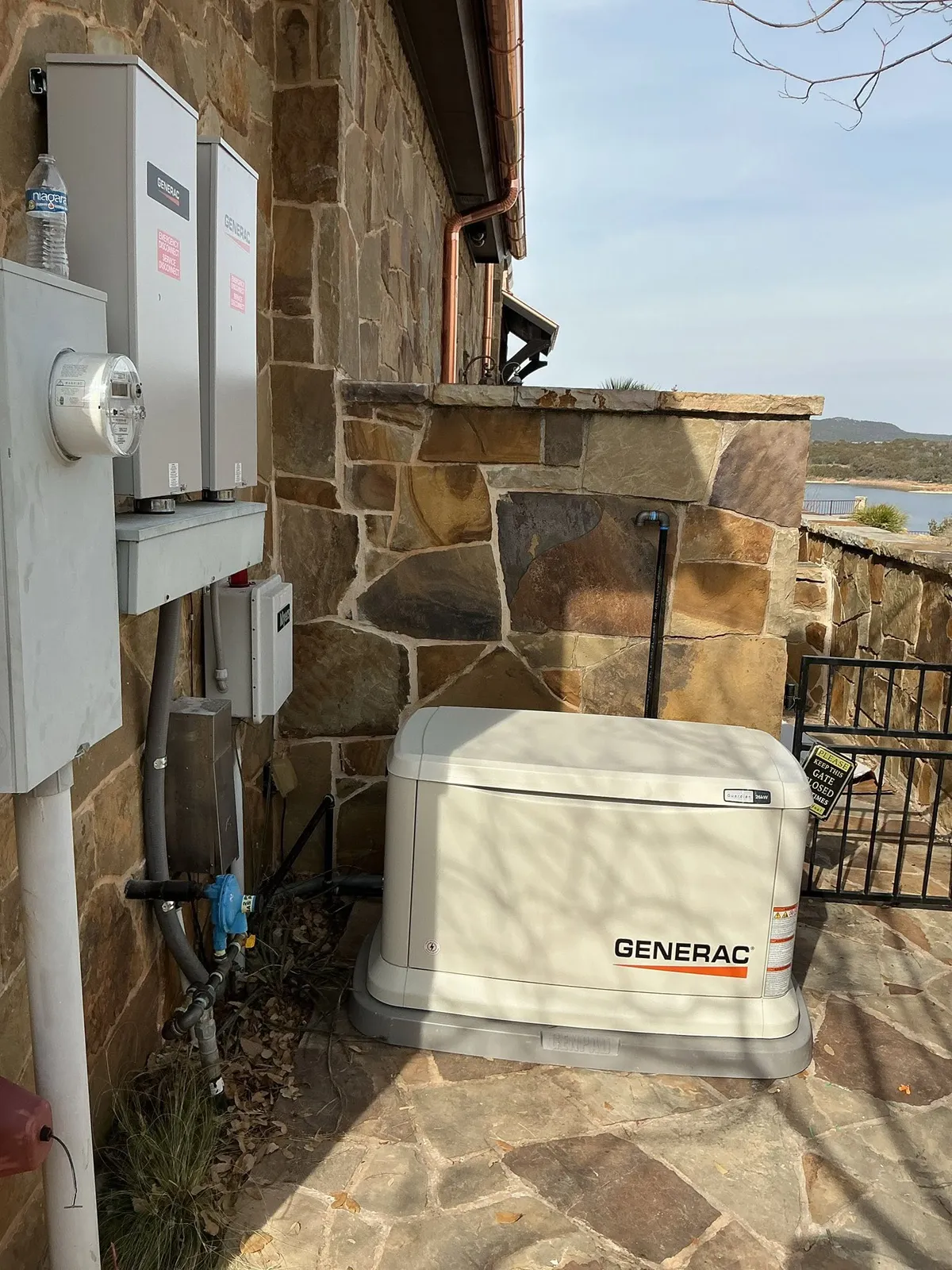 Outdoor electrical service panels mounted on posts in a grassy field with a fence in the background.