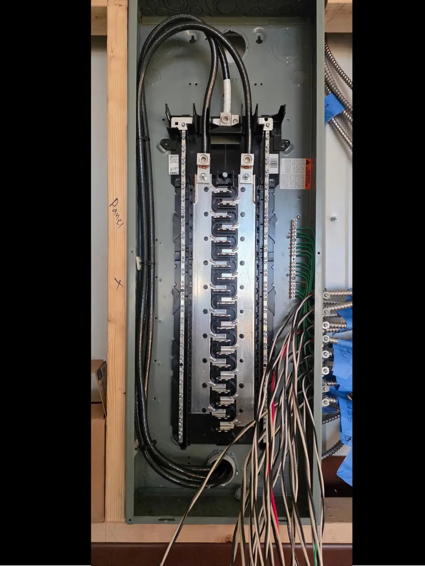 Outdoor electrical meter and main breaker panels mounted on metal struts in a sandy/dirt area.