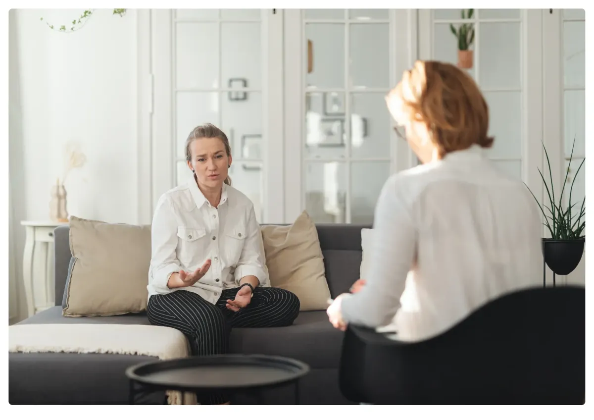 A sunlit living room with soft blush and sage accents, a heart-shaped ceramic on a wooden table, and gentle natural light, evoking warmth and calm.