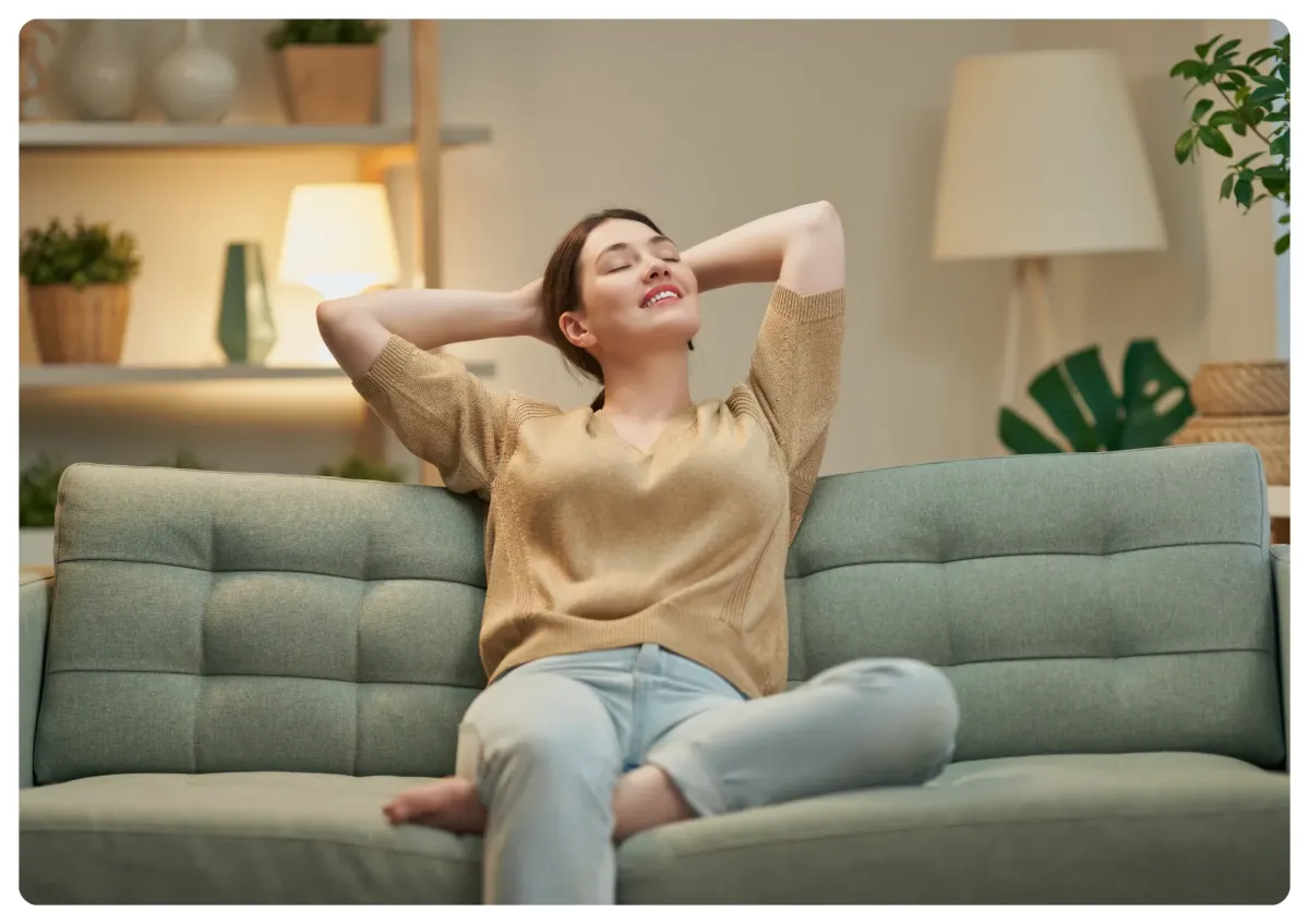A serene, sunlit room with a comfortable lounge chair, soft blue throw, and a gentle plant in the background, evoking calm and tranquility. The setting is designed for relaxation, with natural light and soothing tones, inviting the viewer to unwind.