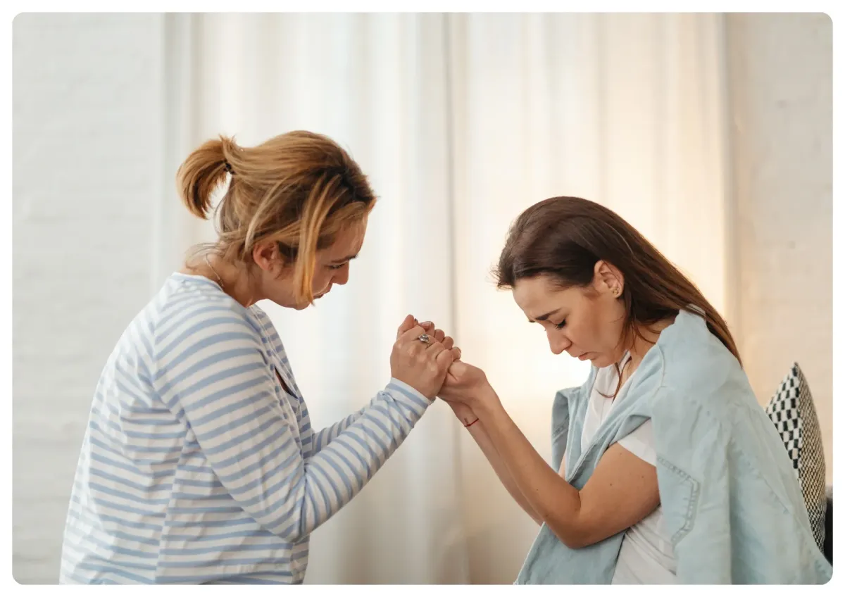 A caring professional gently guiding a client through a relaxation exercise in a softly lit studio, both seated comfortably. The atmosphere is warm and supportive, with subtle blue accents and a sense of trust and calm.