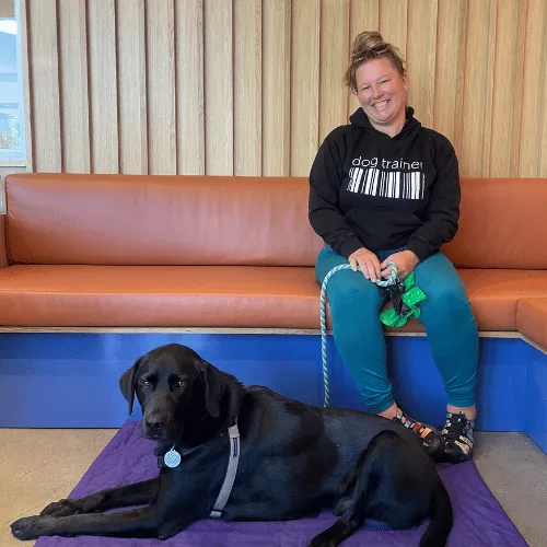 Dog Trainer sitting with black lab during private training session