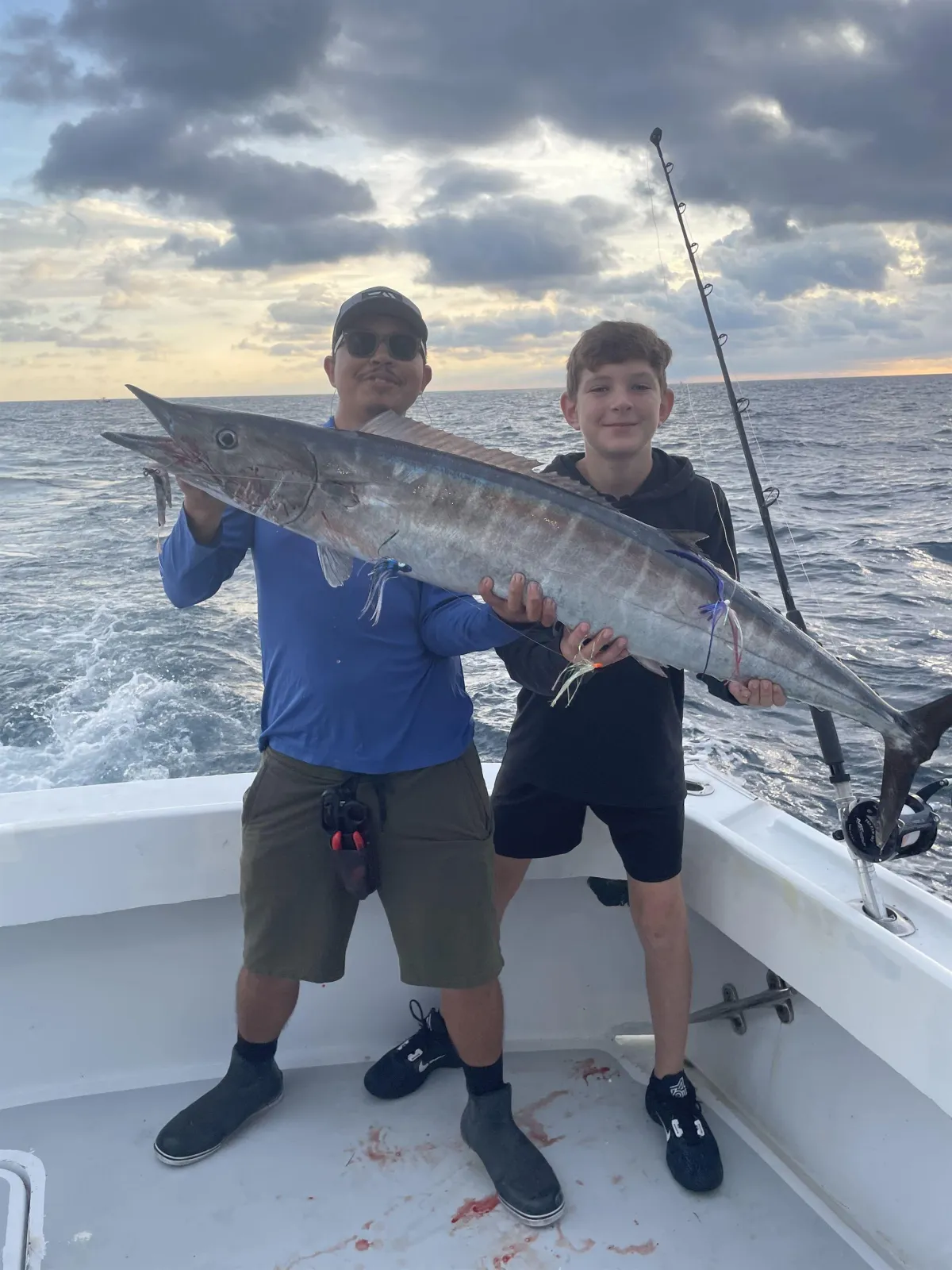Anglers holding a large Wahoo caught on a sport fishing charter off Pompano Beach