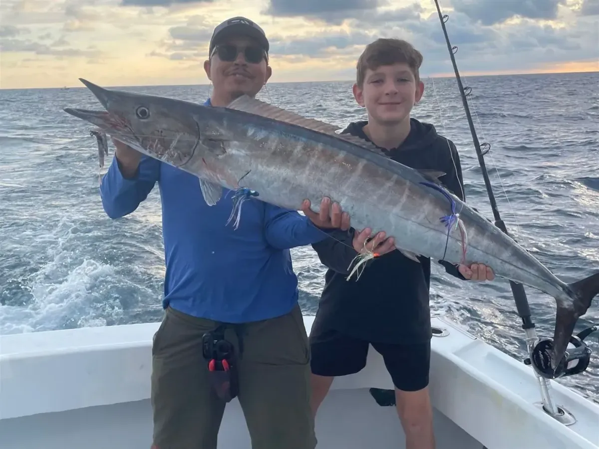 Anglers holding a large Wahoo caught on a sport fishing charter off Pompano Beach