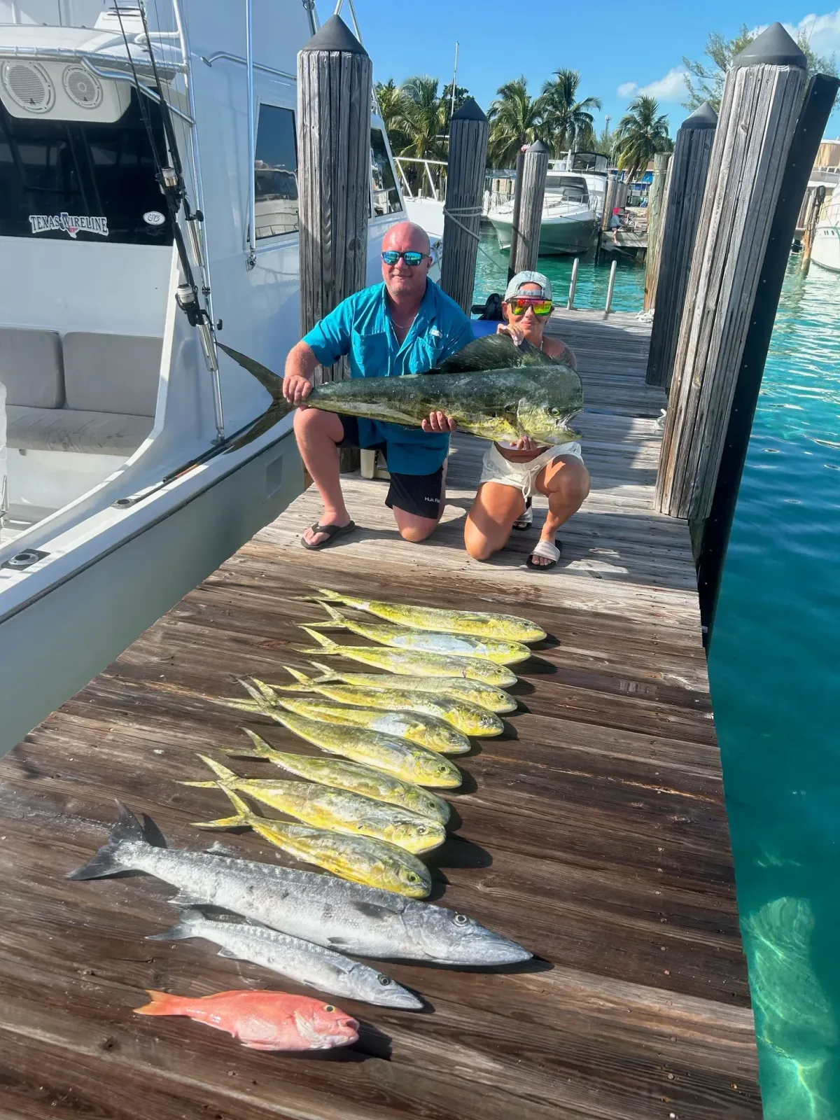 Anglers displaying a huge catch of Mahi Mahi and Barracuda on the dock after a Pompano Beach charter