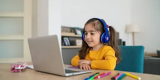 Young student participating in an online reading tutoring session with iReading Tutor using a laptop and headphones
