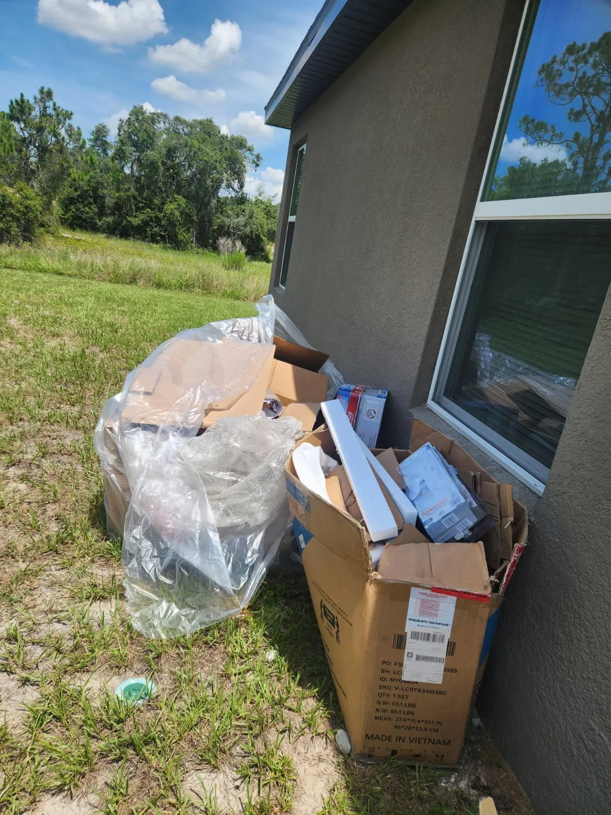 pile of recycle plastic and appliance boxes stacked alongside a home