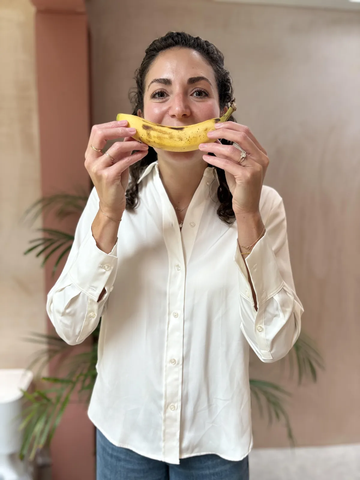 Nikki Fata, registered dietitian holding banana demonstrating how she provides nutrition support to clients using a sarcastic and playful personality