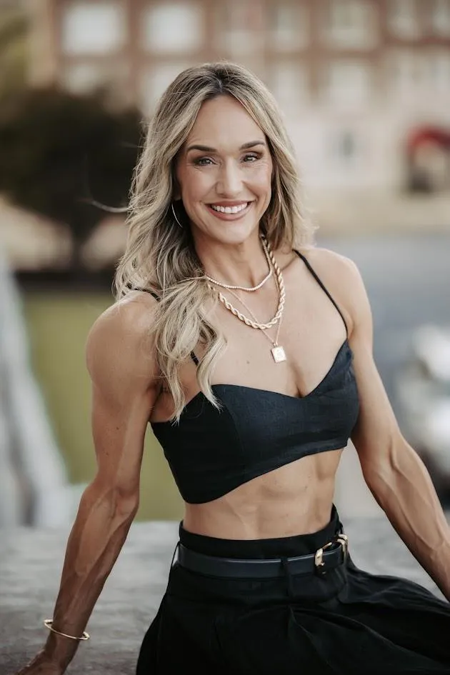 Lindsey Black, founder of Legacy Physiques, smiling confidently in a black dress, representing women's body recomposition and strength coaching for women 35 and older.