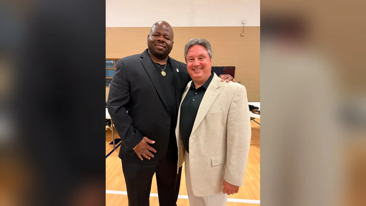 Erik Swenk standing with a fellow attendee in a gym decorated for the Boys II Men Social