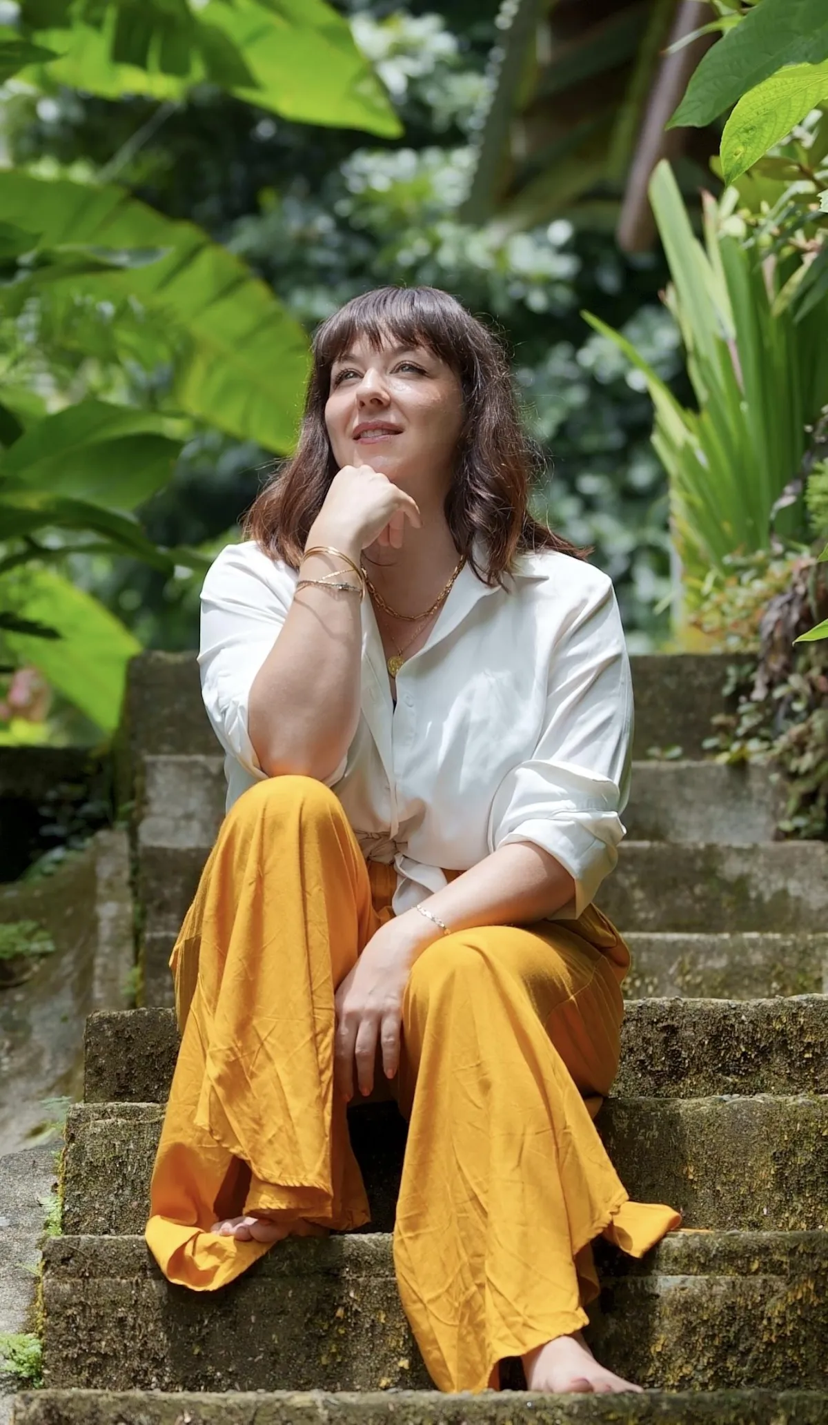 Émilie Caron-Désilets assise sur des marches dans un jardin tropical
