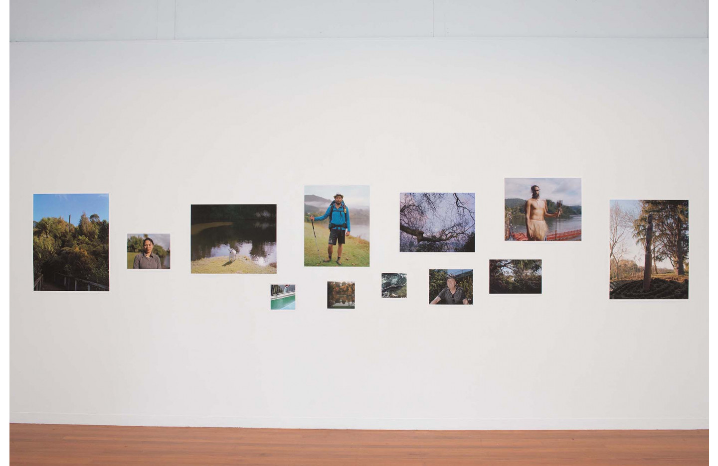 Visitors stand and talk inside a white-walled gallery during the exhibition “INTER” at Gradfest, Unitec, Auckland, viewing a series of small-scale photographic works arranged in an open, informal installation across the space.