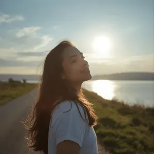 Person standing near the water at sunset, gently smiling and looking back toward the camera, symbolizing calm, reflection, and the sense of clarity that therapy intensives aim to create.
