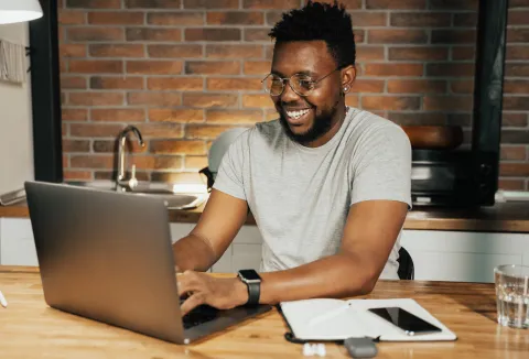 man in green shirt confused at a table with computer
