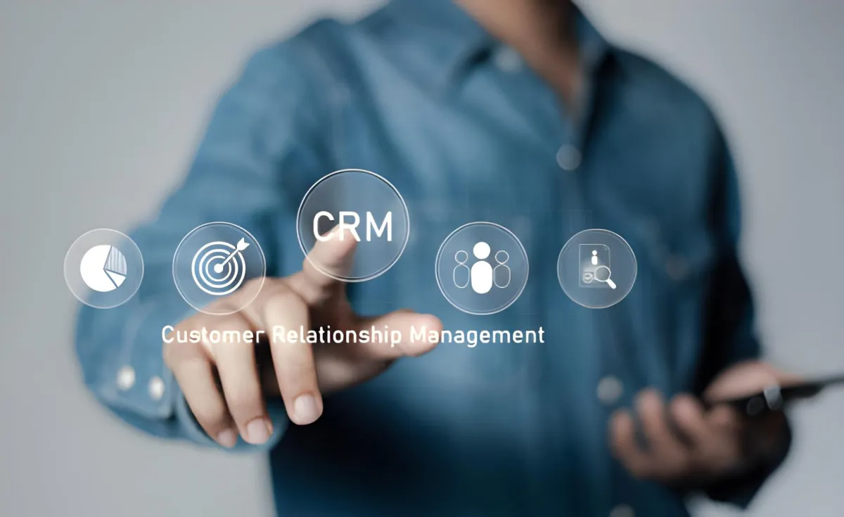 Person pointing at a virtual CRM interface labeled customer relationship management while holding a smartphone.