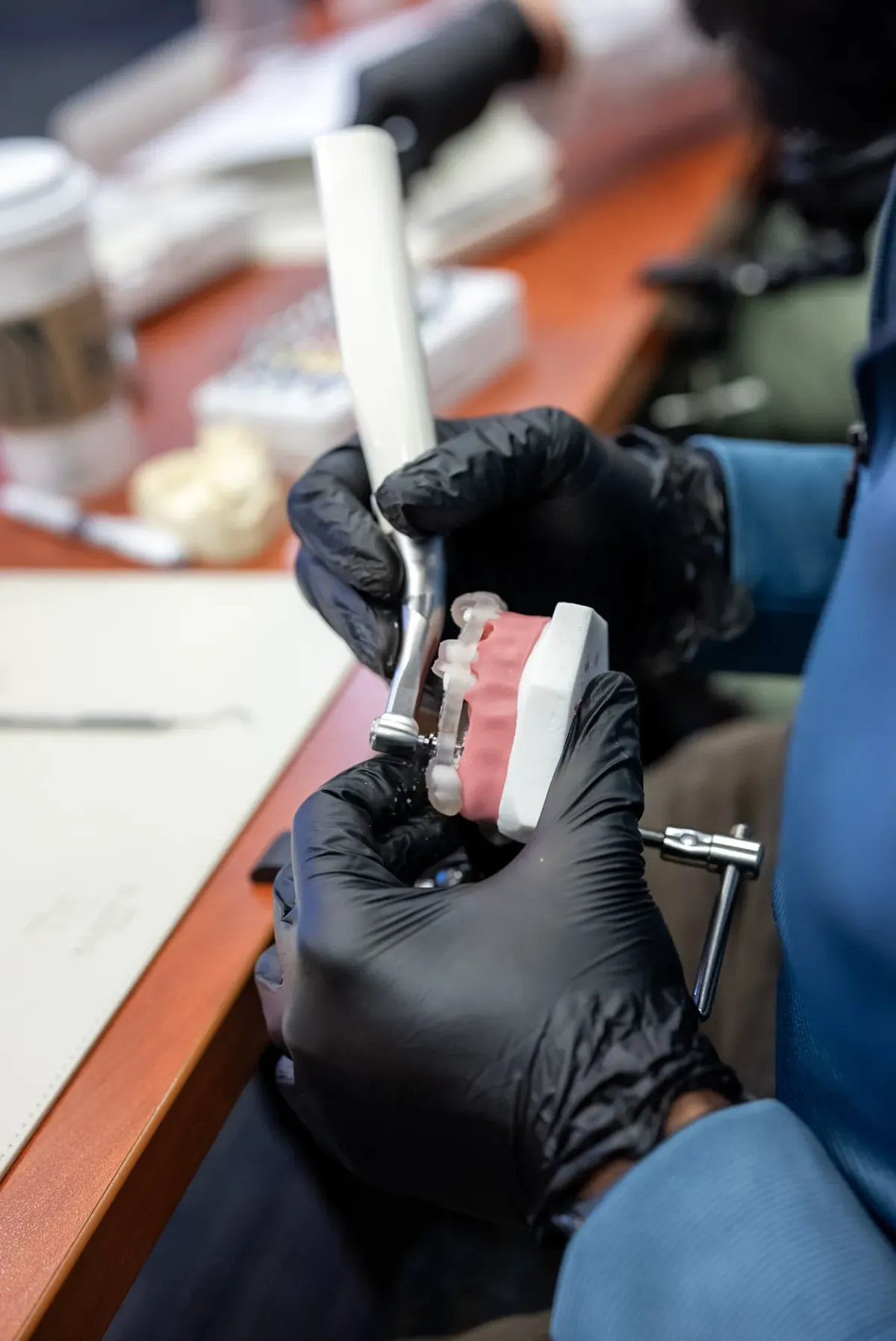 Close up image of a student using tools on a model set of teeth