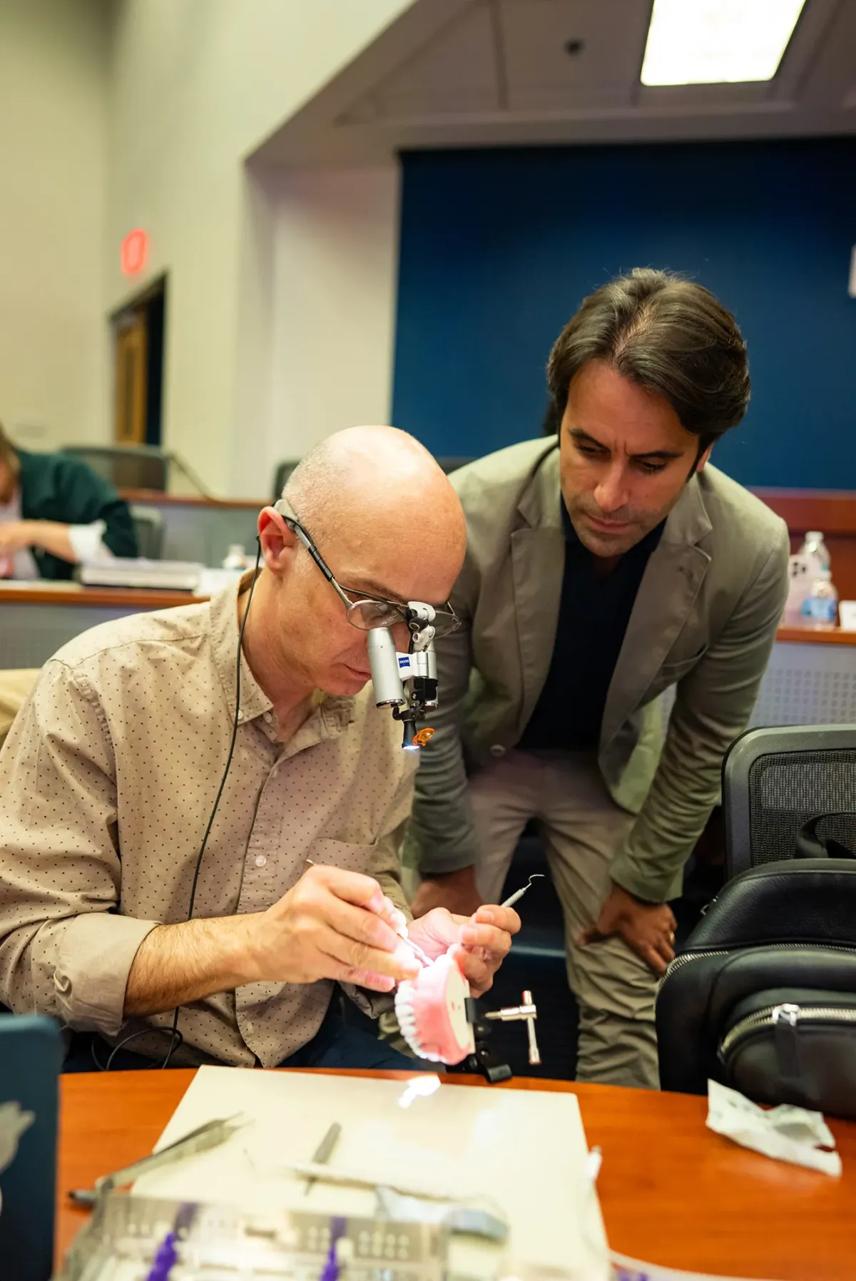 Instructor watches student practice on model