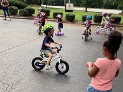 Child rides bike on playground with other children