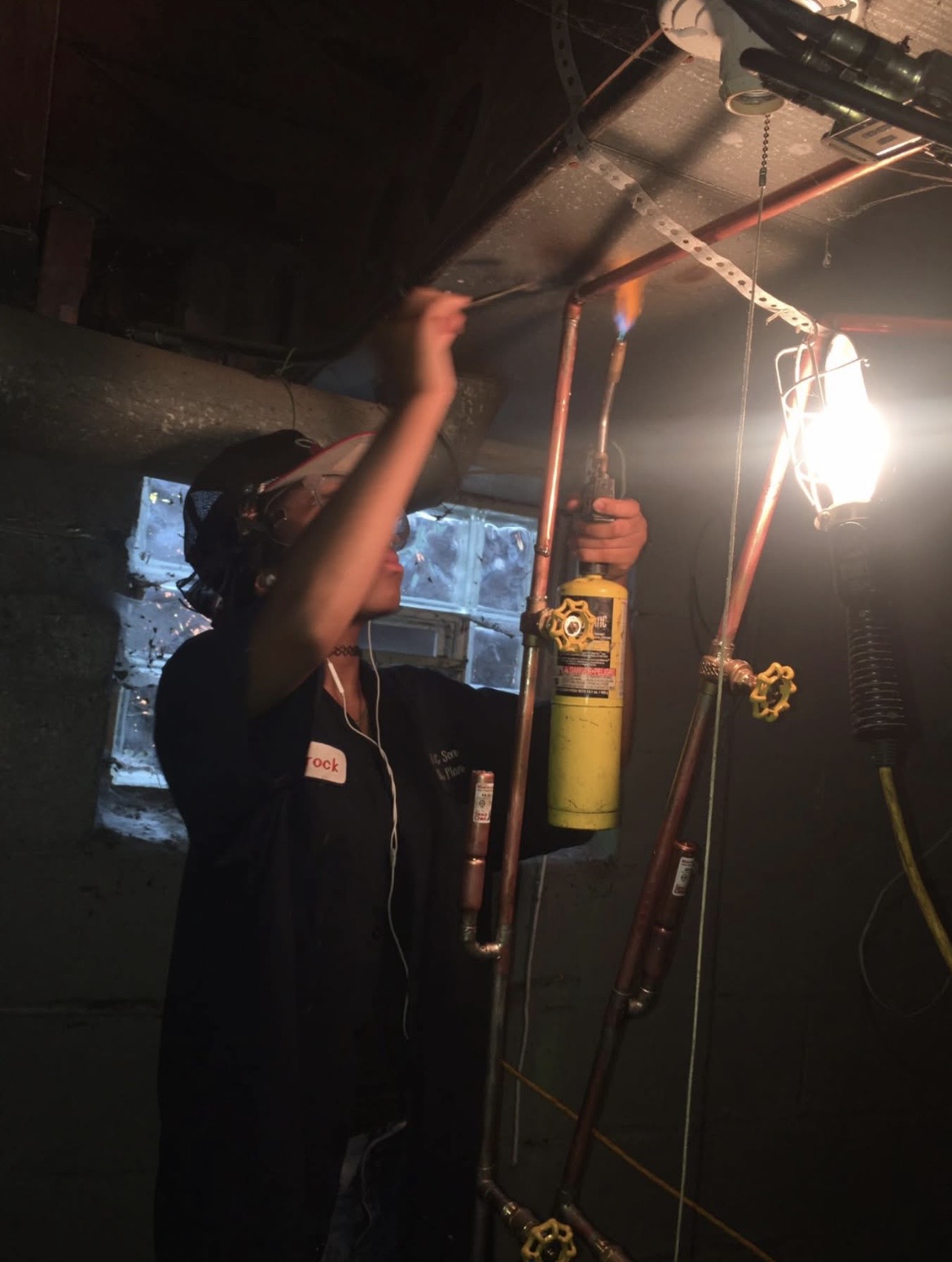 Photorealistic portrait of a Black man working under a sink showing arms and head from a side angle, face not visible