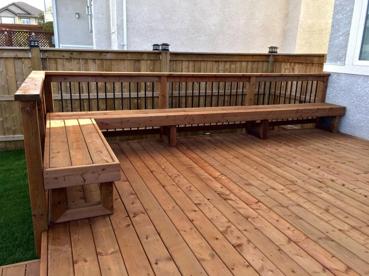 Wooden backyard deck with built-in bench seating and privacy fence along the perimeter.