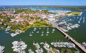 Aerial view of a coastal marina with boats, waterfront homes, and a bridge connecting the shoreline