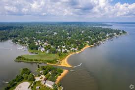 Aerial view of a peninsula neighborhood surrounded by calm water and lush green shoreline.