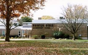Community recreation center building surrounded by trees and a lawn covered in autumn leaves