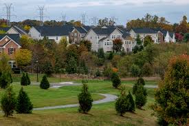 Suburban neighborhood with homes overlooking a grassy park area surrounded by trees
