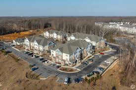 Aerial view of a suburban apartment or townhome community surrounded by wooded land