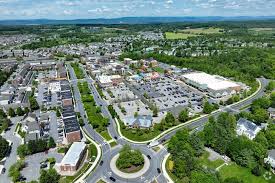 Aerial view of a suburban town center with shops, roundabouts, and residential neighborhoods nearby.