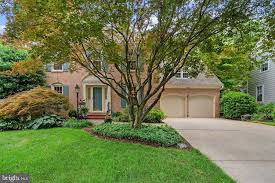 Two-story home with well-maintained landscaping, large tree, and driveway in a suburban neighborhood.