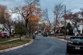 Tree-lined residential street with parked cars and homes during autumn