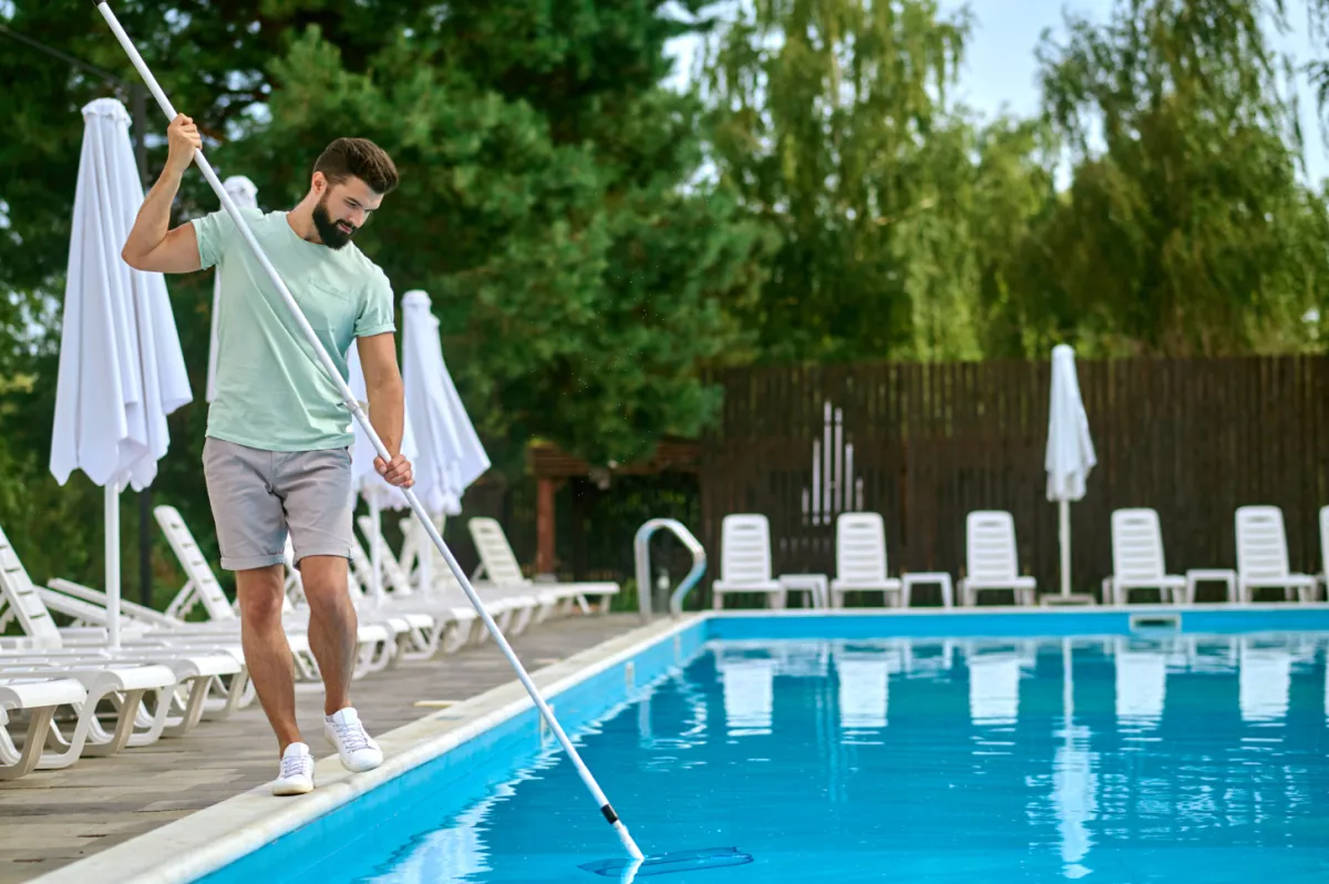 "Pool technician expertly cleaning a residential pool, ensuring crystal-clear water and a well-maintained swimming area."