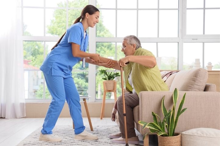 A caregiver assisting an elderly person with a cane for Home care after hip replacement surgery.