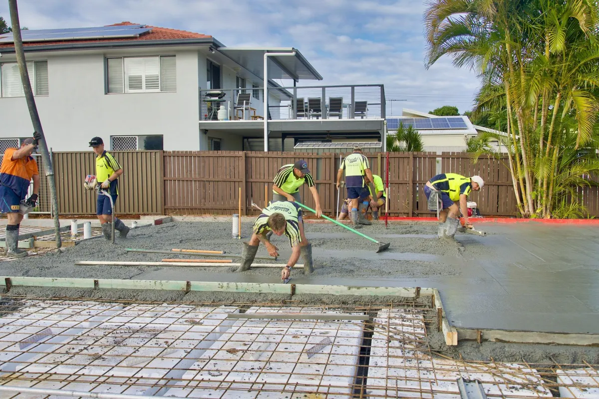 Crew of concrete workers troweling freshly-poured pavement concrete.