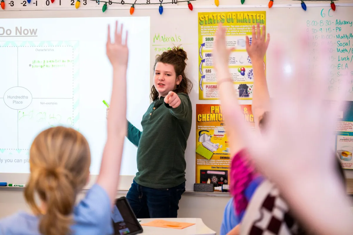 A diverse team of three professionals, two women and one man, are seated at a modern white table in a sunlit office, reviewing inquiries on laptops. The background features large windows and subtle blue accents, conveying a responsive, attentive atmosphere. The composition is candid and collaborative.