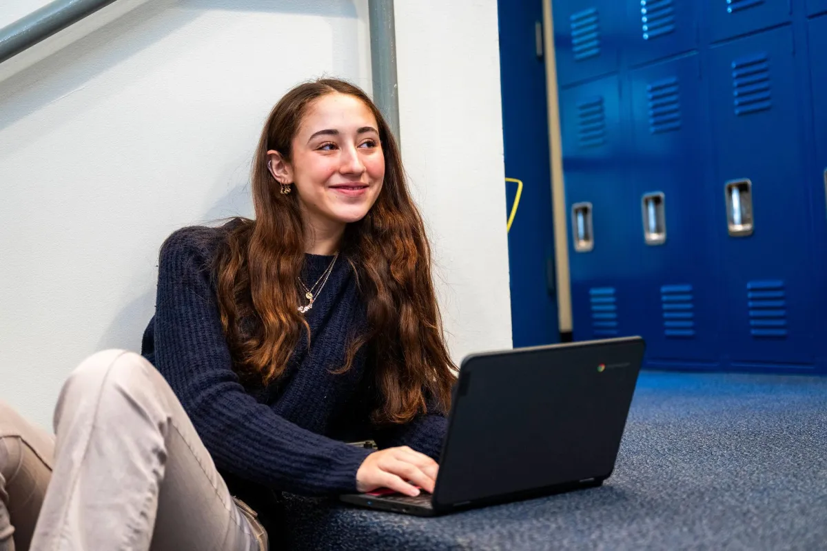 A close-up of a laptop screen displaying a newsletter signup form with the company's branding. The hands of a person are visible typing on the keyboard, and the workspace includes a notepad and a pen, with a clean, modern aesthetic and natural light.