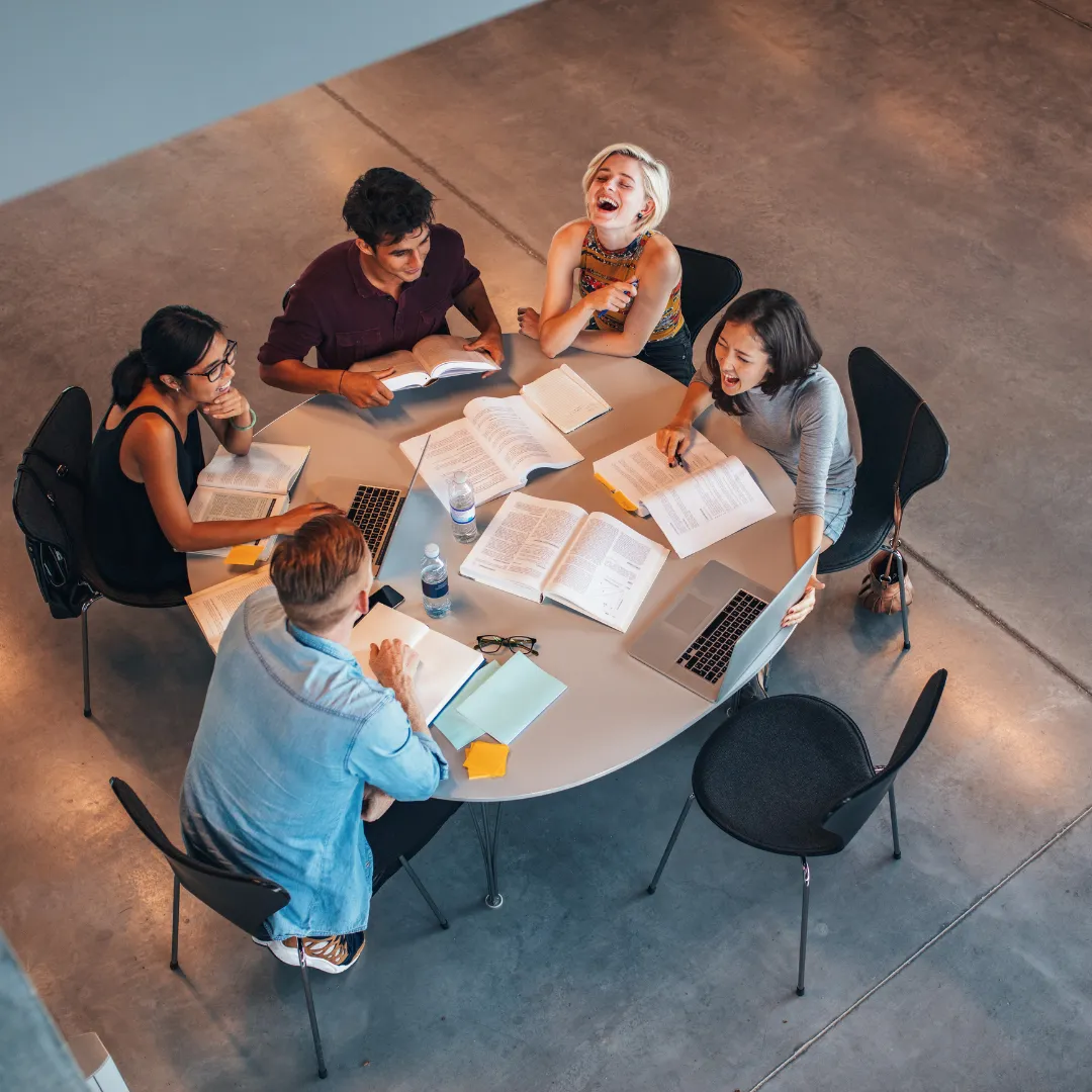 Group of diverse individuals engaged in a collaborative brainstorming session around a table, studying and discussing ideas, representing community support for Christian entrepreneurs in business strategy and alignment with God-given assignments.