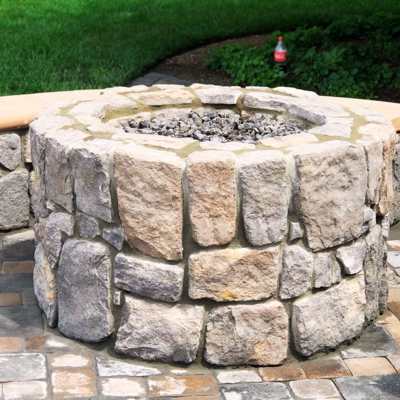 Custom stone fire pit with surrounding seating wall built for backyard gatherings in Raleigh