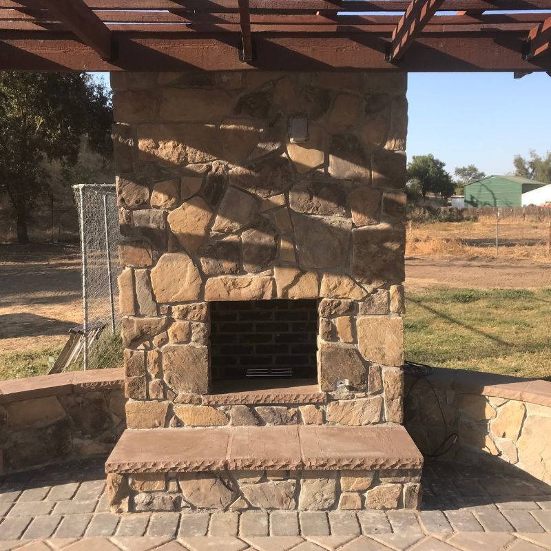 Stately stone outdoor fireplace creating focal point for patio living room in Raleigh backyard