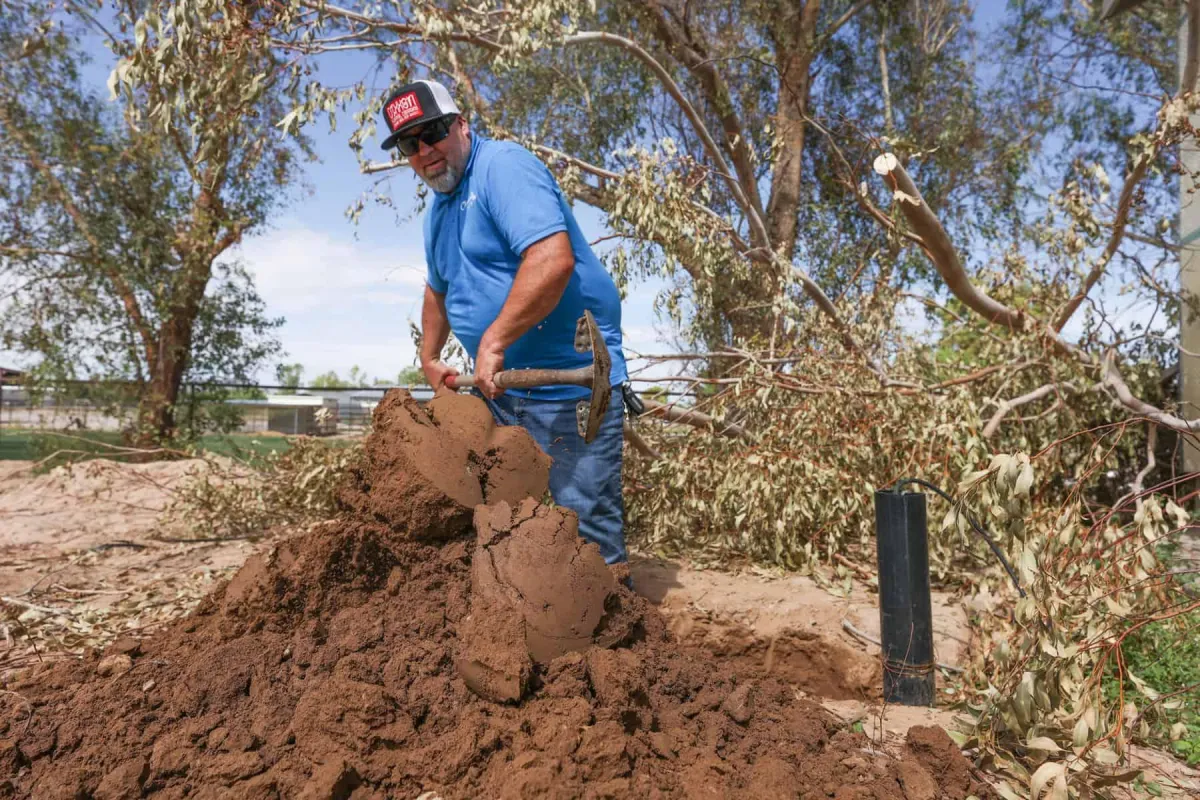 Worker inspecting a septic system outdoors with a shovel.