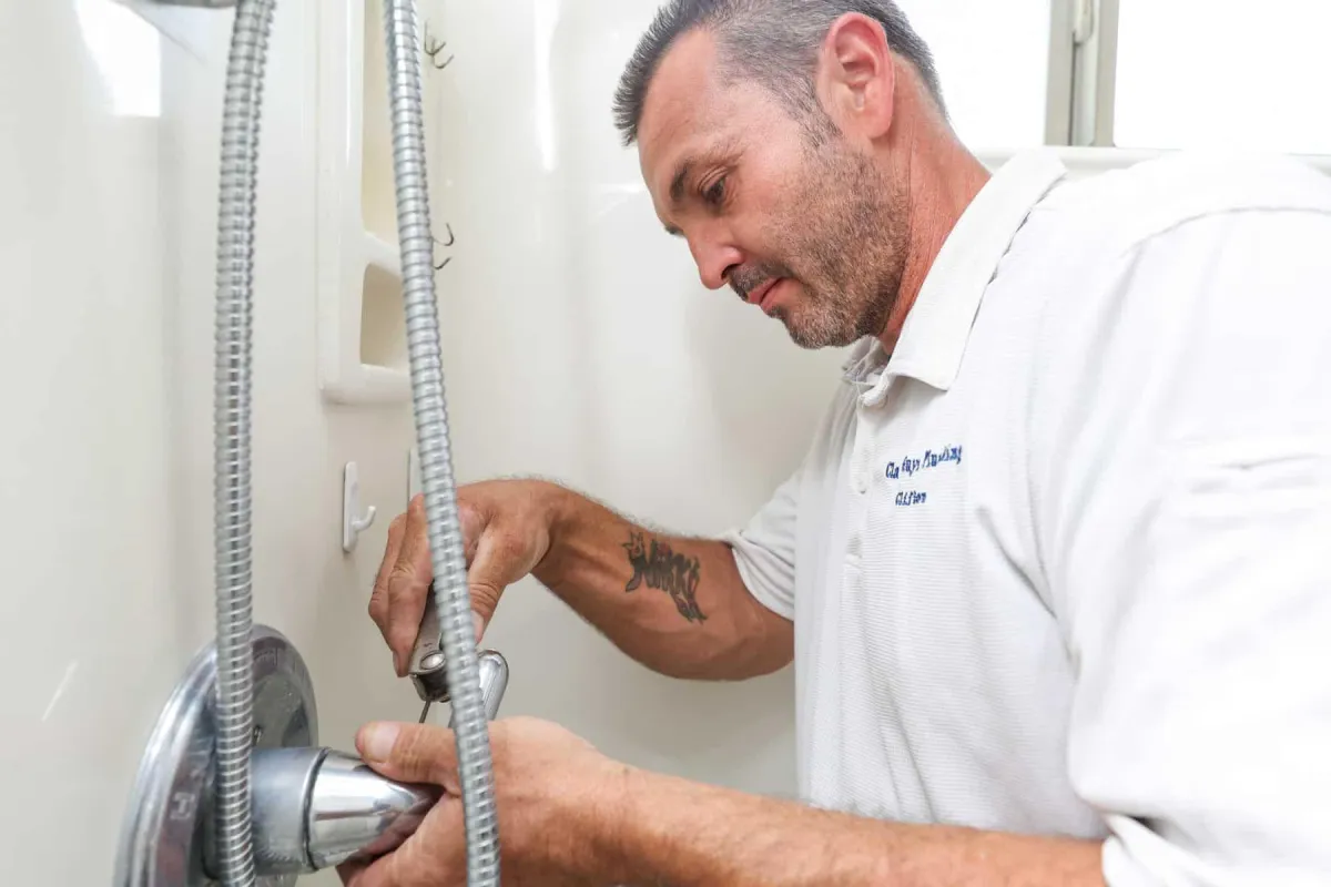 Technician adjusting plumbing during a bathroom remodel project.