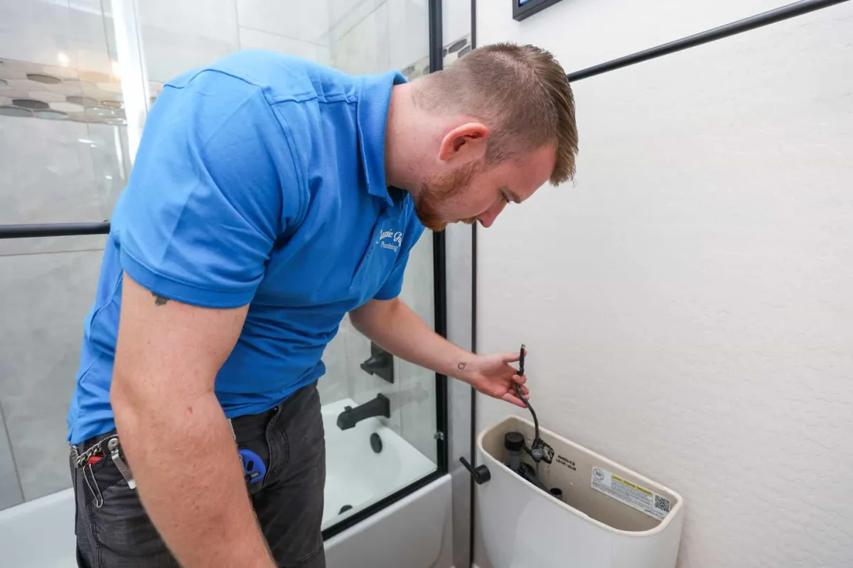 Plumber inspecting the inside of a toilet tank.