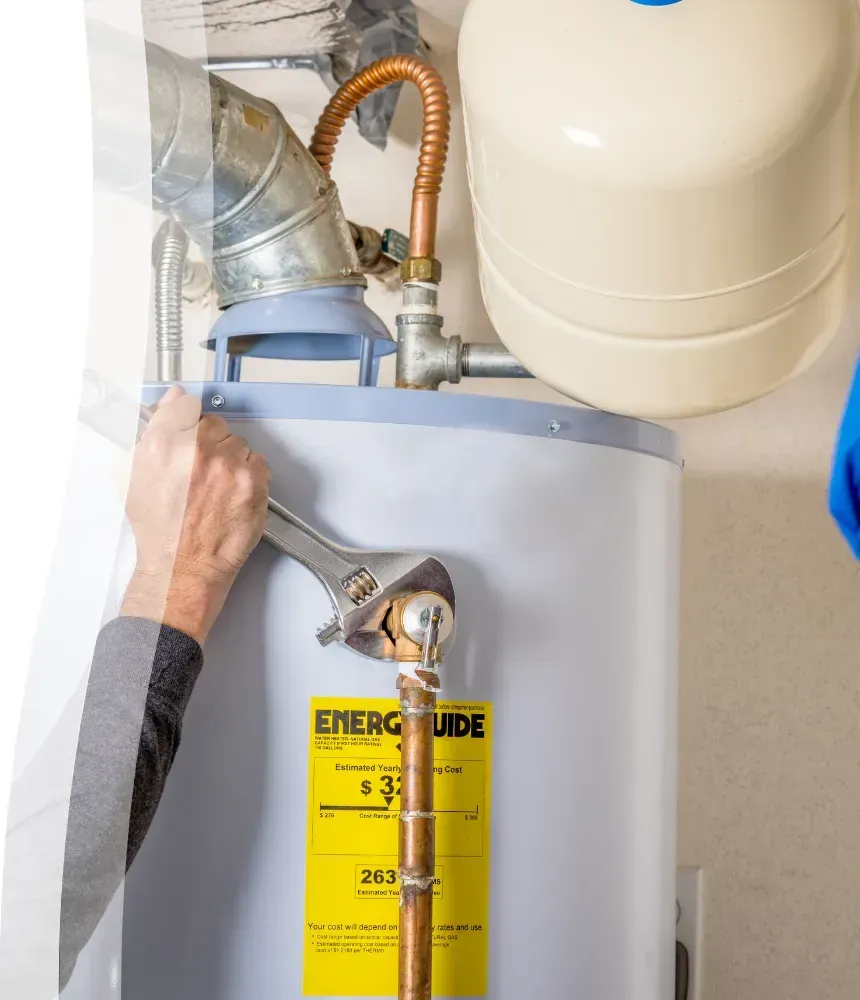 Plumber using a wrench to tighten a connection on a residential water heater in Arizona.