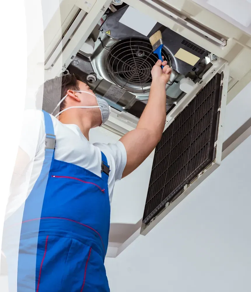 Technician cleaning air conditioning evaporator unit during routine HVAC maintenance