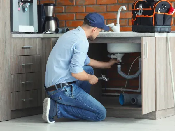 Plumber fixing kitchen sink plumbing in Arizona. 