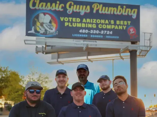 Classic Guys Plumbing team standing together in front of Classic Gu billboard in Arizona