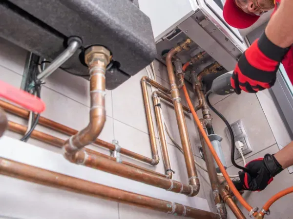 Technician installing residential gas line connections with copper pipes